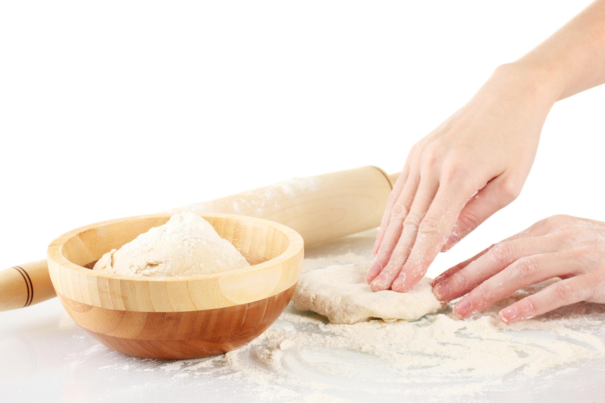 Hands kneading dough on wooden board
